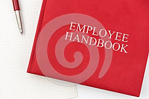 Employee Handbook or manual with a pen and paper on a white table in an office.