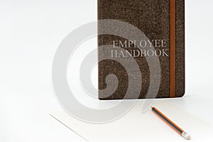 Employee Handbook or manual with a pen and paper on a white table in an office.