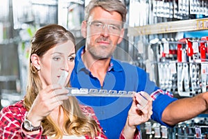 Employee of hardware store helping customer in ironware departme photo