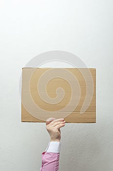 Employee holding blank cardboard against bright wall.Concept of strike action and stoppage, empty cardboard for text