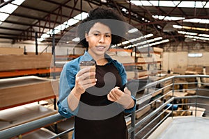 Employee holding cup of coffee and standing at warehouse