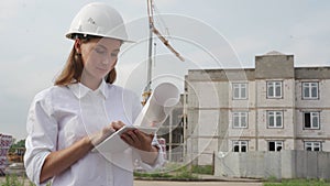 Employee, inspector or engineer inspects a building on a construction site using a tablet computer, a protective helmet