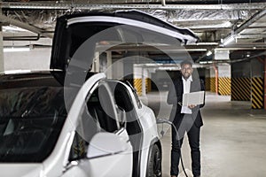 Employee with laptop working in EV underground garage