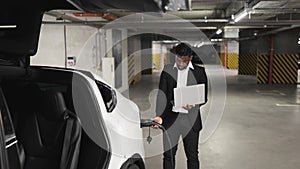 Employee with laptop working in EV underground garage