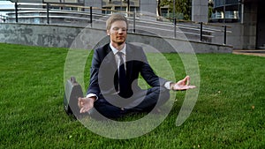 Employee meditating on green lawn, unity with nature and relaxation in city