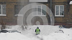 Employee monitors the safety of work for others. Occupational Safety and Health. Throwing white snow from the roof of a