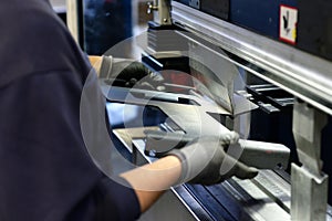 Employee operates bending machine in a metalworking company - bending of sheet metal for further processing photo