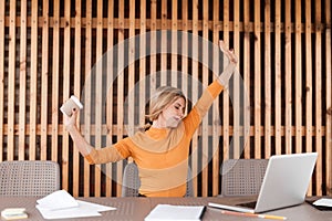 Employee pretty young woman relax in workplace. Stretching her arms