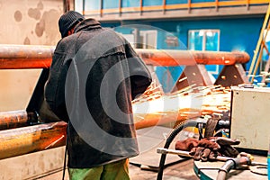 An employee at the production site performs metal cutting. sparks fly to the right