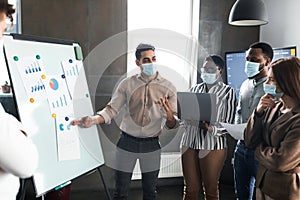 Employee in protective face mask presenting business strategy on whiteboard