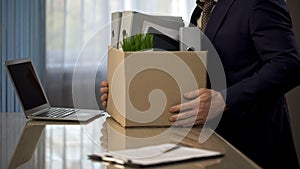 Employee putting his stuff from work desk in carton box, leaving job, retirement