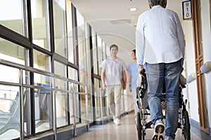 Employee and residents walking in hallway of nursing home