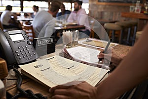 Employee at a restaurant writing down a table reservation photo
