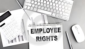EMPLOYEE RIGHTS text written on notebook on grey background with chart and keyboard , business concept