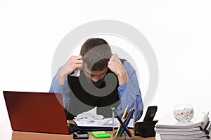Employee sits clasping his head with his fists at the office table
