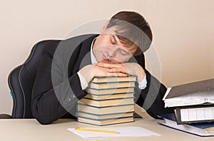 Employee sleeping on the books with documents at the table in the office