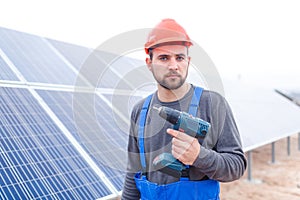 A employee of the solar cell station, holds a drill in his hands.