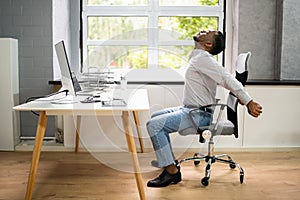 Employee Stretching At Office Desk