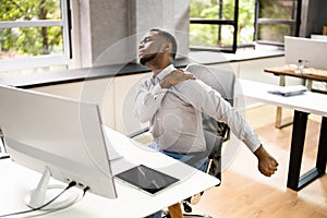 Employee Stretching At Office Desk