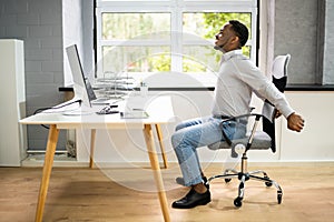 Employee Stretching At Office Desk