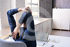 Employee Stretching At Office Desk