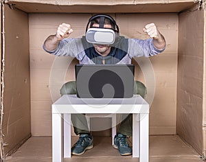 Employee with virtual reality glasses working in his home cardboard office