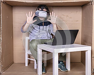 Employee with virtual reality glasses working in his home cardboard office