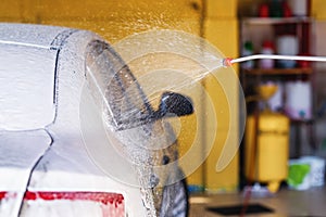 Employee washes the automobile with foam machine at the garage. Carwash concept.