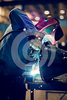 Employee welding steel with sparks using mig mag welder