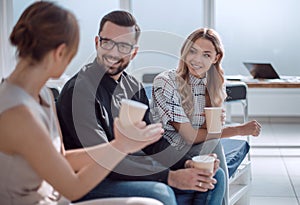 employees of the company with coffee glasses sitting in the office lobby