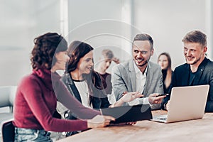 Employees discuss working documents sitting at a Desk