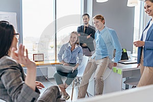 Employees gather in the office and listen to their colleague speak