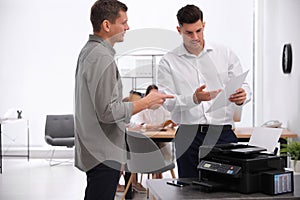 Employees near new modern printer in office