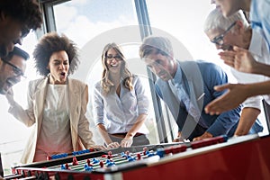 Employees playing table soccer indoor game in the office during break time