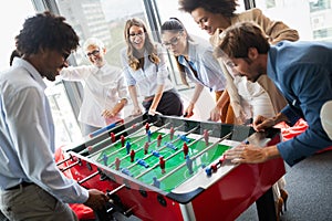 Employees playing table soccer indoor game in the office during break time