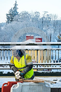 Employees of the road service in special yellow vests perform work on the repair of the roadway. Road repairs in difficult winter