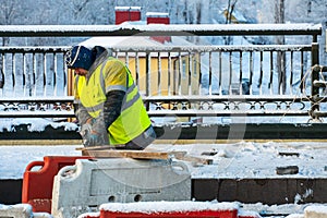 Employees of the road service in special yellow vests perform work on the repair of the roadway. Road repairs in difficult winter