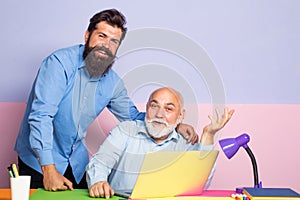 Employees sit at office desk look at laptop screen cooperating in office. Couple of two office workers working at laptop