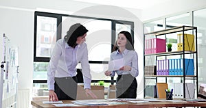 Employees spread papers on table working on project together