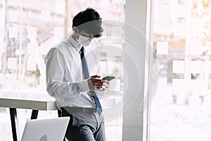 Employees standing at work using their phones while wearing masks during the virus outbreak