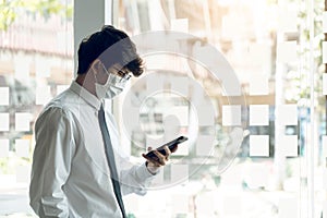 Employees standing at work using their phones while wearing masks during the virus outbreak