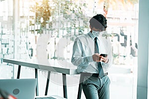 Employees standing at work using their phones while wearing masks during the virus outbreak