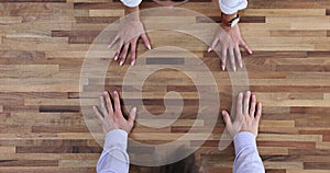 Employees of successful company put hands on wooden table