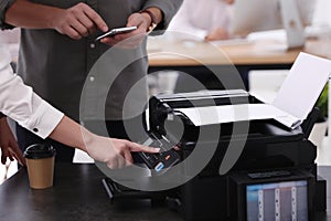 Employees using modern printer in office, closeup