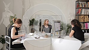 Employees work in creative office at their desktops and computers.