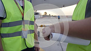 Employees in yellow dickey shake hands. Airport workers shakes hands. Engineers shake hands after checking. Airport