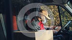 Parcel delivery man using mobile phone in car