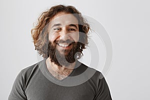 Employer is proud of his loyal employees. Portrait of glad attractive businessman with curly hair and beards smiling