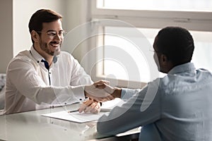 Employer shaking hands starting job interview greeting african applicant