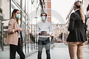 Employers standing in social distance wearing face mask looking at each other and talking